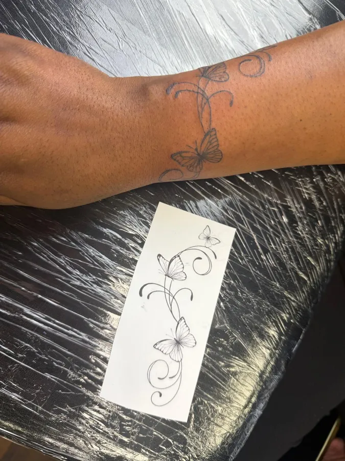 Butterfly and vine tattoo beside its original stencil design